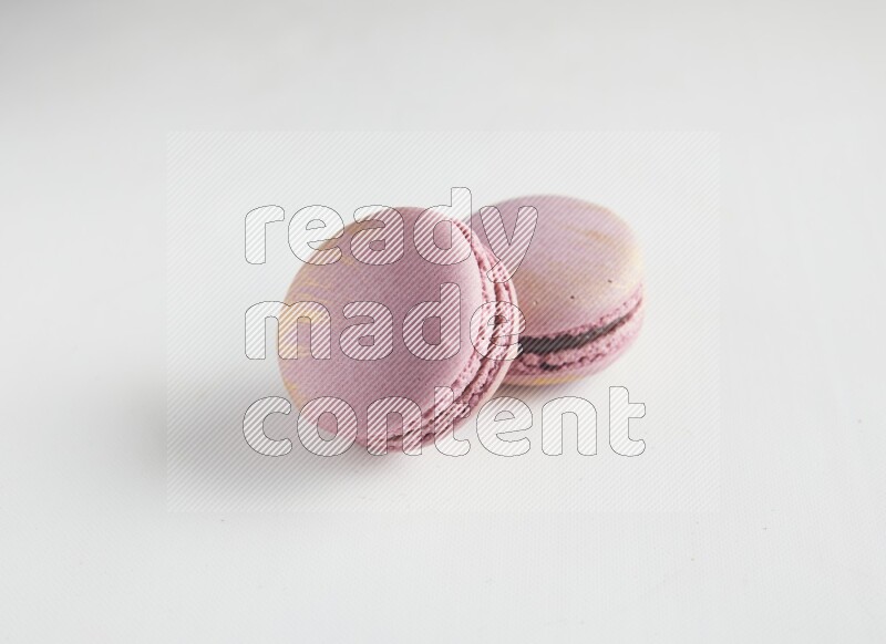 45º Shot of two Purple Strawberry macarons on white background
