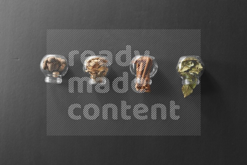 أوراق الغار وزنجبيل مجفف وقرفة وجوزة الطيب في أوعية زجاجية علي خلفية سوداء