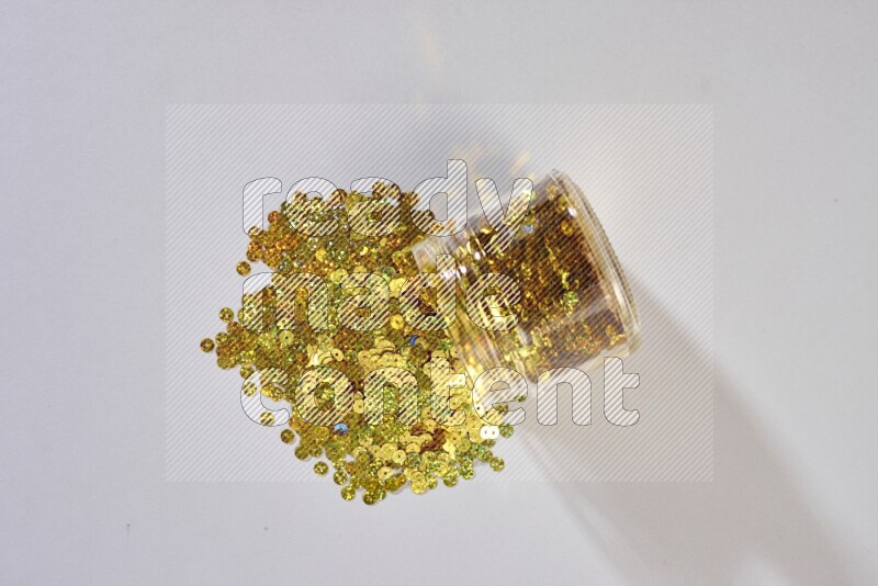 Colored flat sequins in a glass jar on grey background