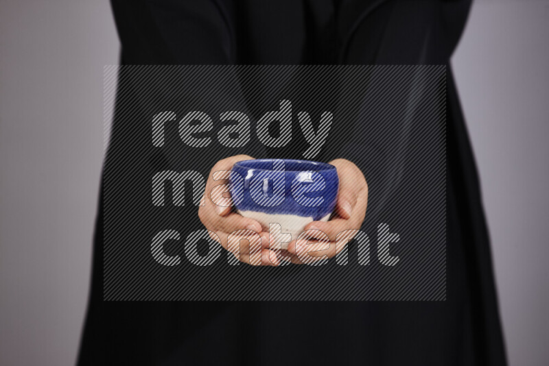 A woman in black abaya holding different pottery essentials in different positions