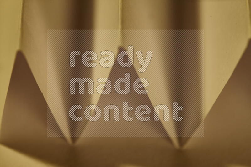 صورة مجردة مقربة تظهر طيات ورقية هندسية حادة بتدرجات الوان دافئة