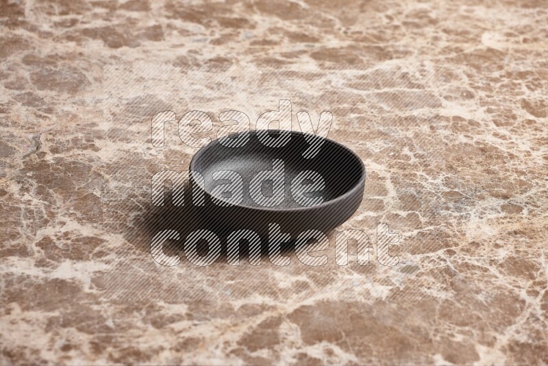 A black pottery bowl on beige marble background