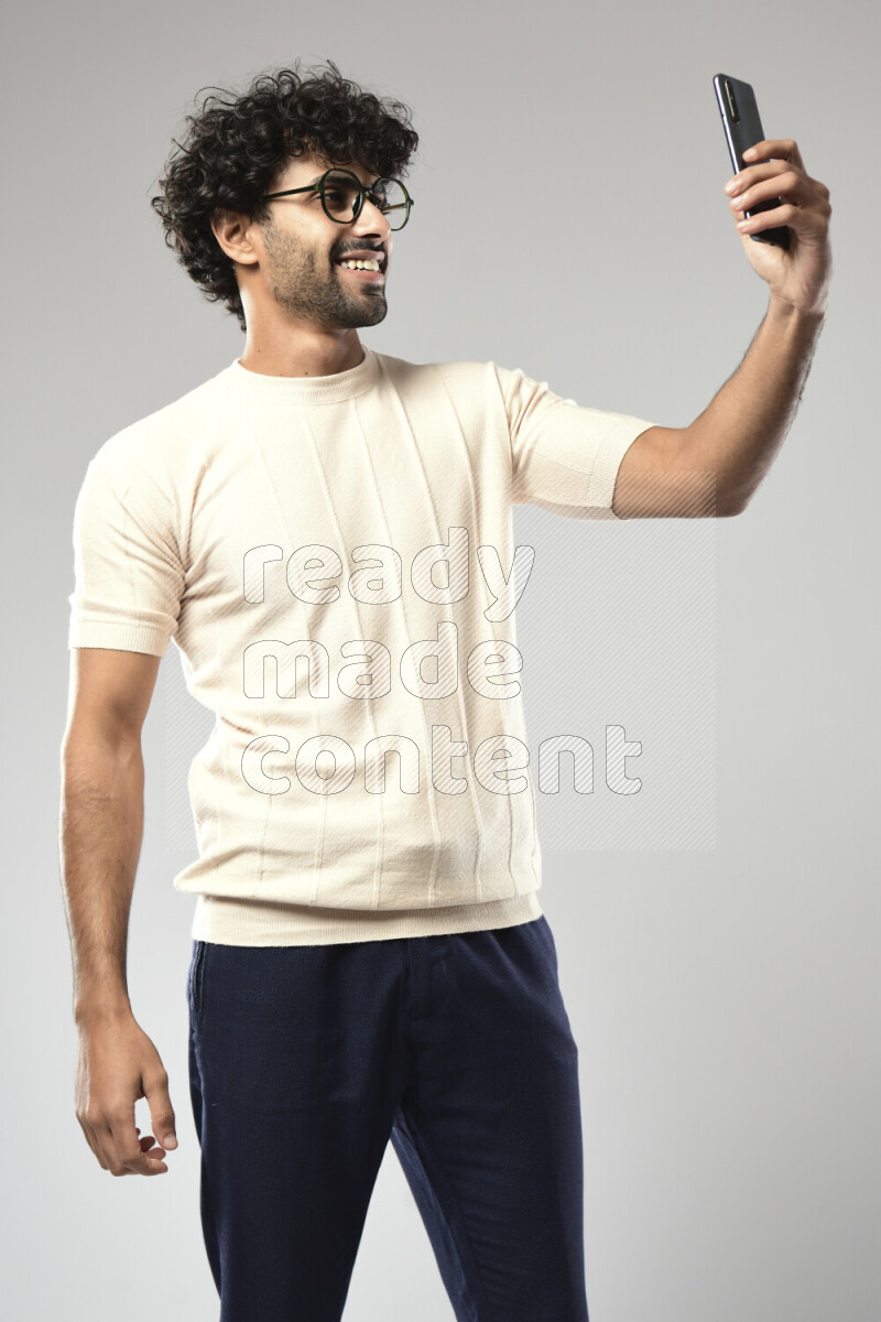 A man wearing casual standing and taking a selfie on white background