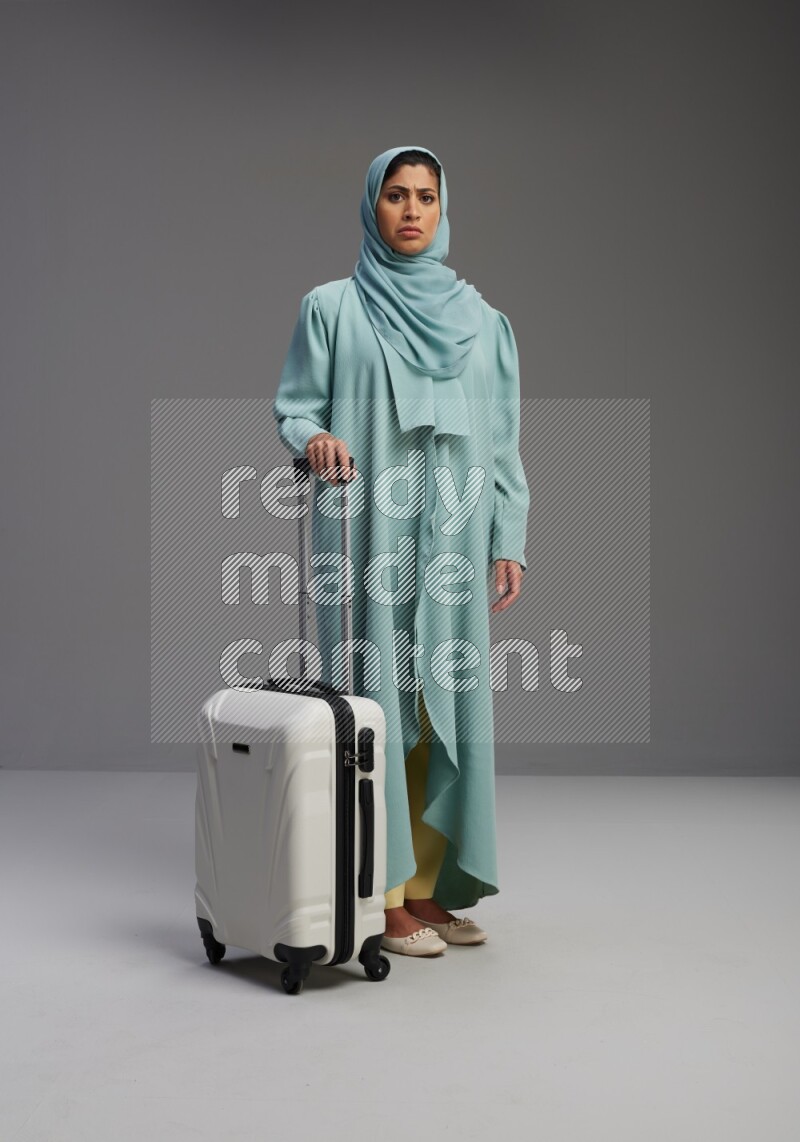 Saudi Woman wearing Abaya standing holding Travel bag on Gray background