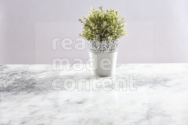 Artificial plant in white decorative pot on grey marble background
