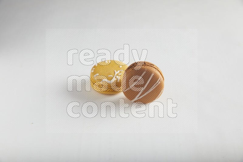 45º Shot of of two assorted Brown Irish Cream, and Yellow Piña Colada macarons on white background