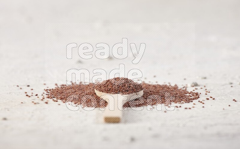 A wooden spoon full of garden cress seeds on a textured white flooring