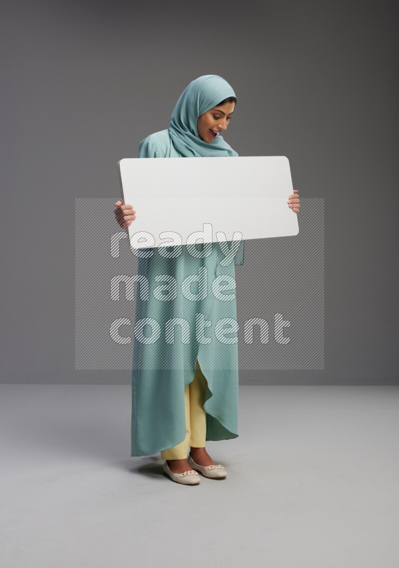 Saudi Woman wearing Abaya standing holding board on Gray background