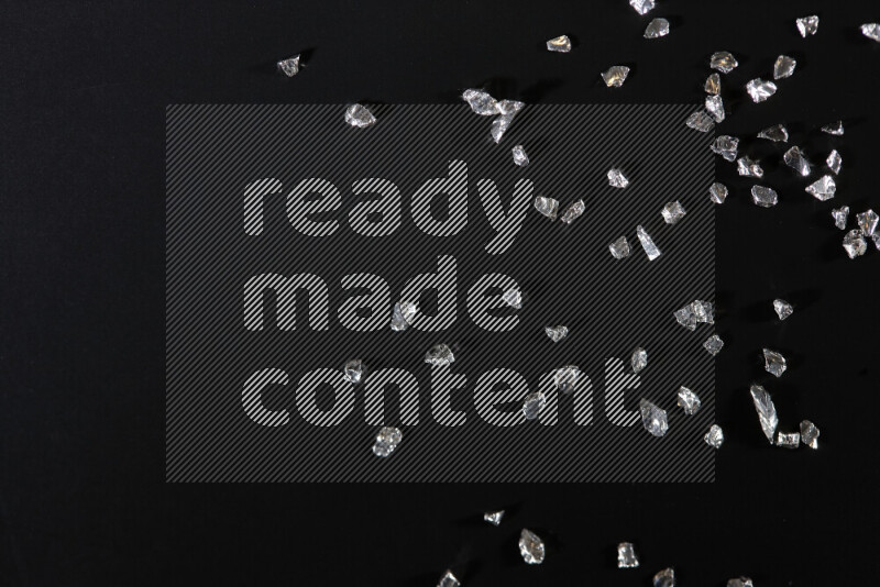 Silver shimmering fragments of glass scattered on a black background