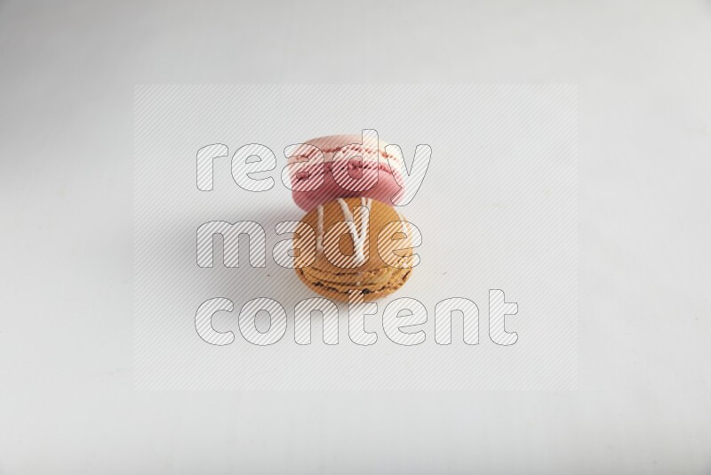 45º Shot of of two assorted Brown Irish Cream, and Pink Litchi Raspberry macarons on white background