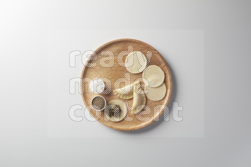 two closed sambosas and one open sambosa filled with meat while salt and black pepper aside in a wooden dish on a white background
