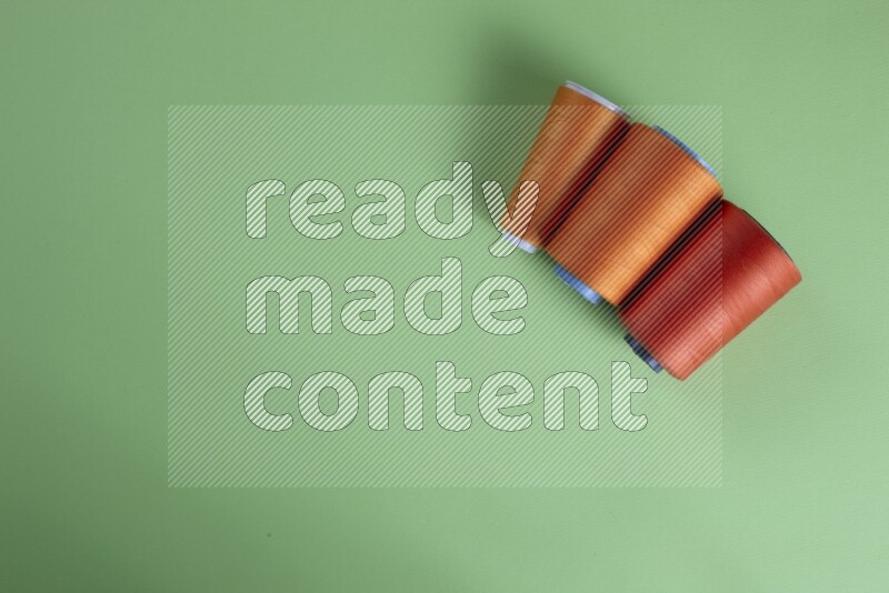 An orange collection of sewing and tailoring tools arranged on a green background