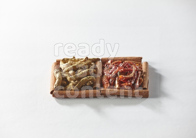 مربعان من أعواد القرفة ممتلئان بالفلفل الحار المجفف وأصابع الكركم علي خلفية بيضاء