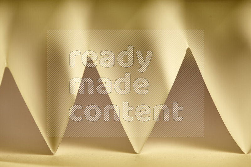 A close-up abstract image showing sharp geometric paper folds in warm gradients