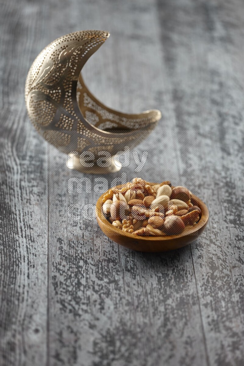 A silver lantern with different drinks, dates, nuts, prayer beads and quran on grey wooden background