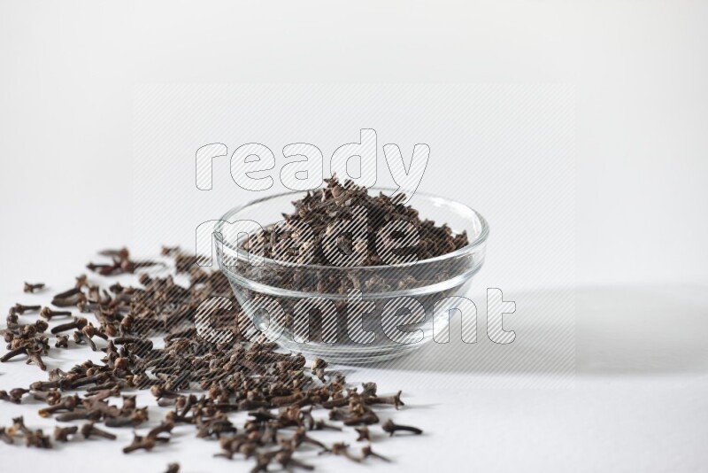 A glass bowl full of cloves on a white flooring