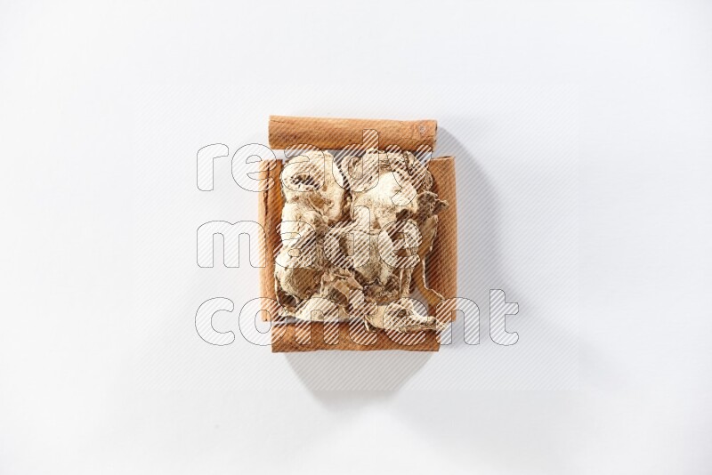 A single square of cinnamon sticks full of dried ginger on white flooring
