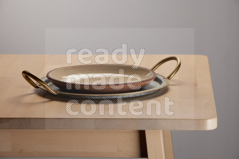 multicolored plate placed on a rounded stainless steel tray with golden handels on the edge of wooden table