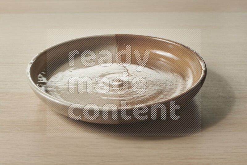 A multicolored pottery plate on light wooden background