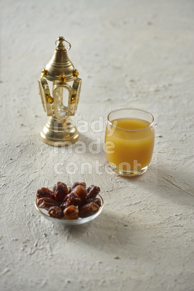 A golden lantern with different drinks, dates, nuts, prayer beads and quran on textured white background