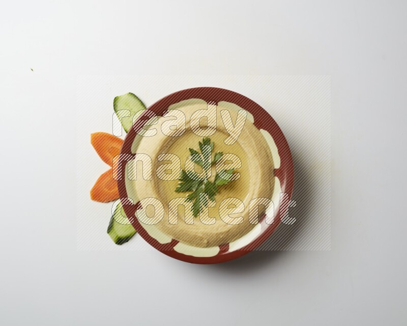 Hummus in a traditional plate garnished with parsley on a white background