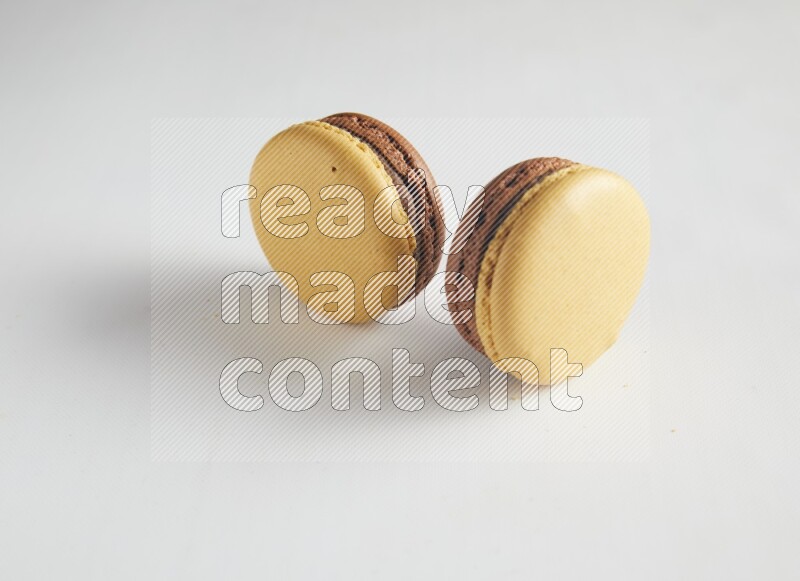 45º Shot of two Yellow and Brown Chai Latte macarons on white background