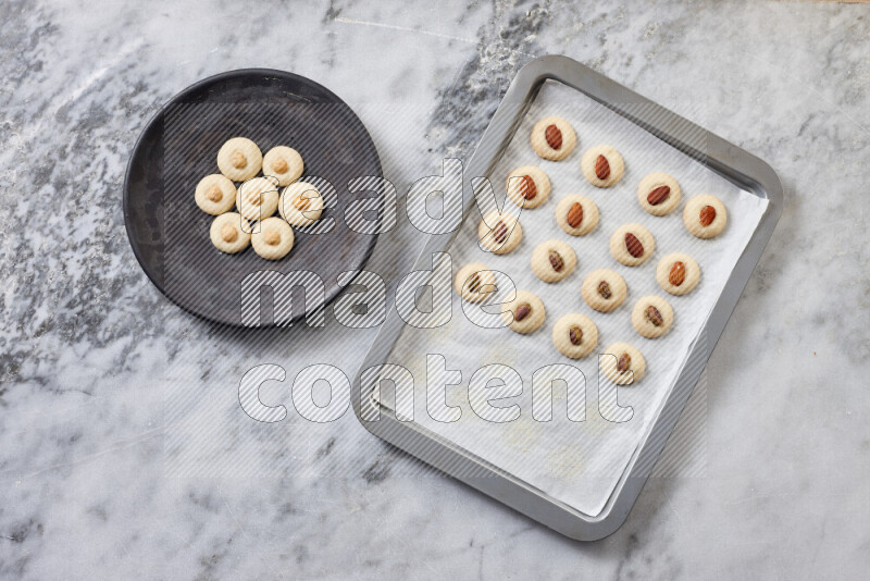 Ghoriba step by step with its ingredient, flour, powdered sugar, ghee and nuts on grey marble background