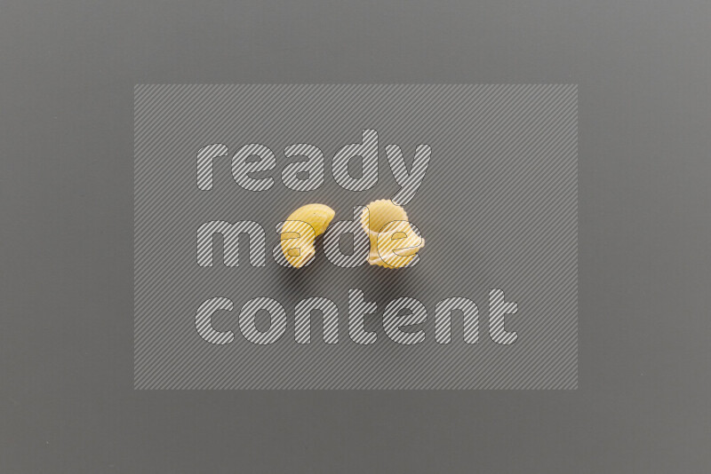 Elbow pasta with other types of pasta on grey background