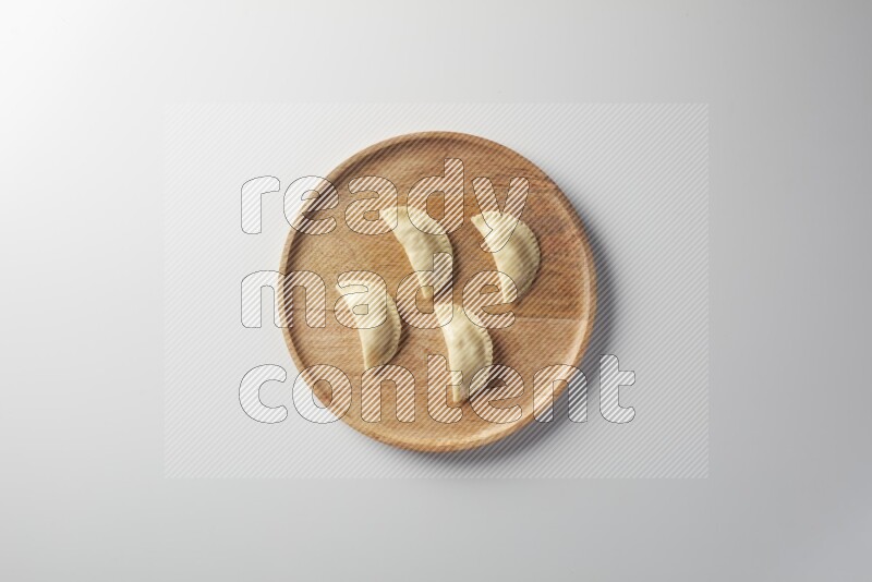 Four Sambosas on a wooden round plate on a white background