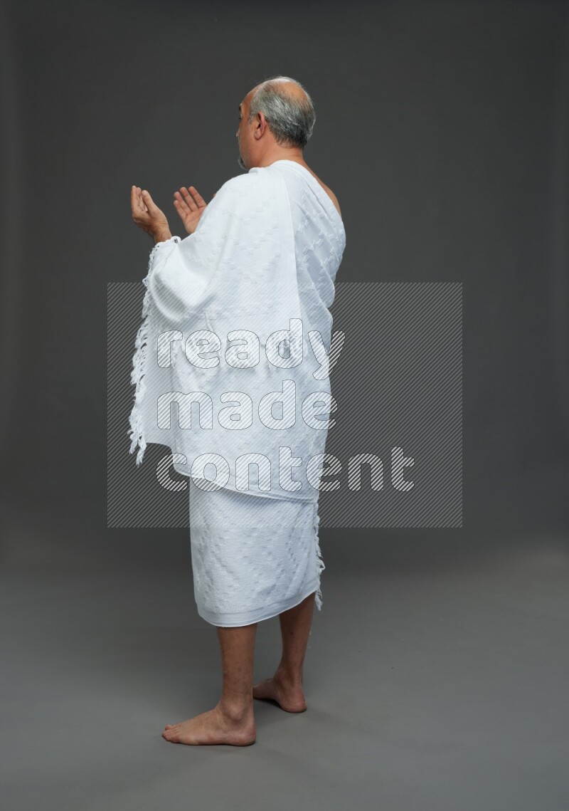 A man wearing Ehram Standing dua'a on gray background