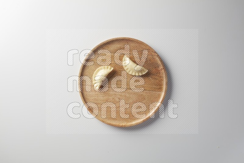 Two Sambosas on a wooden round plate on a white background