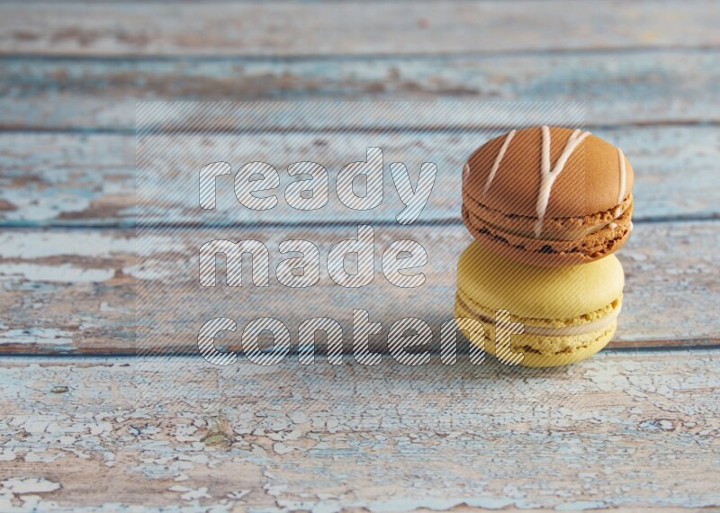 45º Shot of of two assorted Brown Irish Cream, and Yellow Lime macarons on light blue background