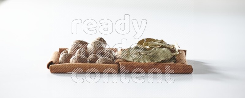 2 squares of cinnamon sticks full of bay laurel leaves and nutmegs on white flooring