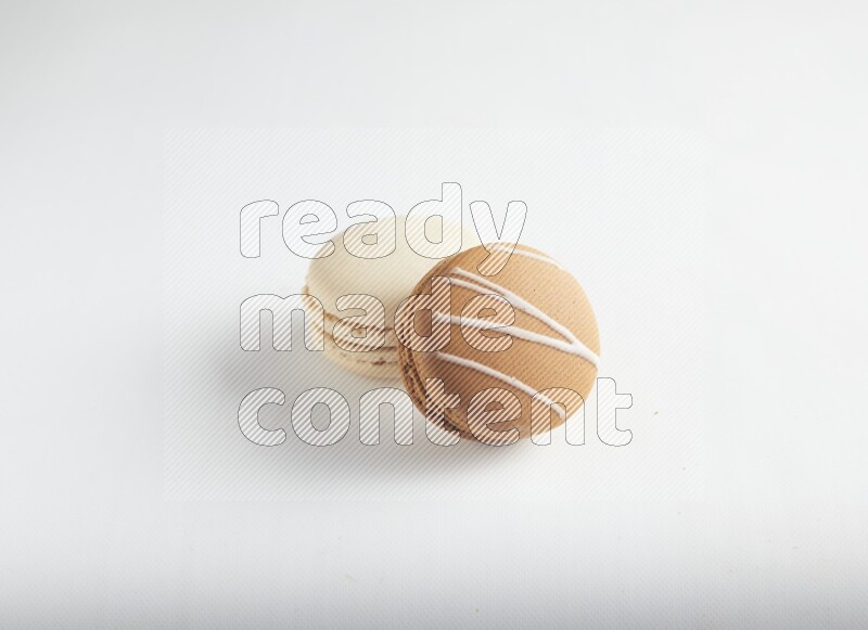 45º Shot of of two assorted Brown Irish Cream, and White Caramel fleur de sel macarons on white background
