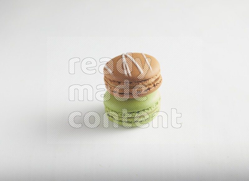45º Shot of of two assorted Brown Irish Cream, and Green Pistachio macarons on white background