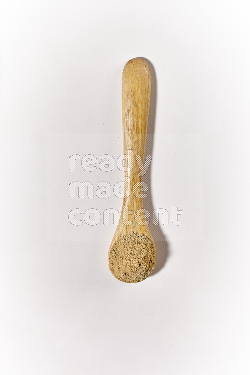 A wooden spoon full of ground ginger powder on white background