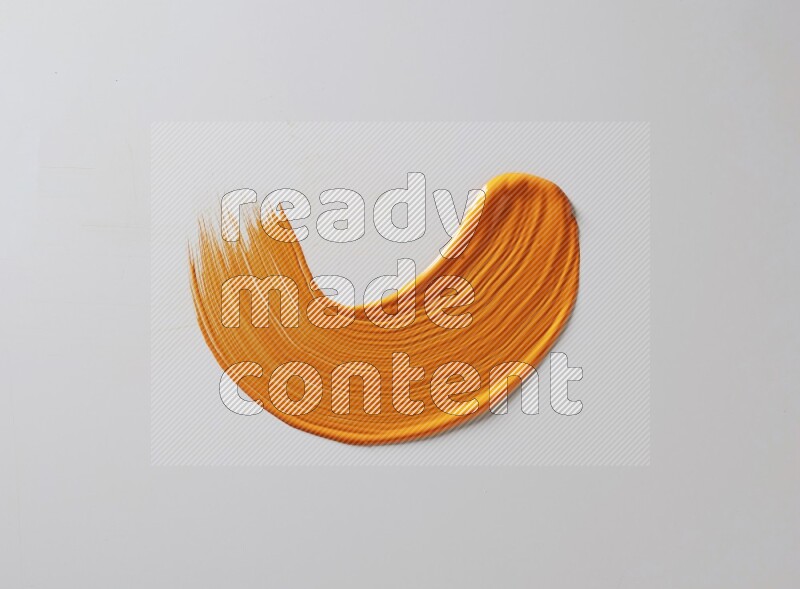 An orange curved painting brush stroke on a white background