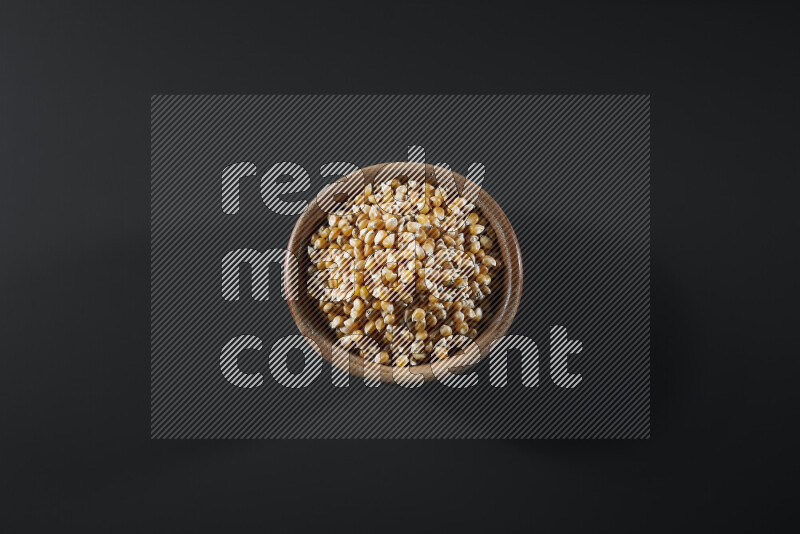 Dry corn kernels in a wooden bowl on grey background