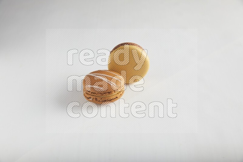 45º Shot of of two assorted Brown Irish Cream, and Yellow, and Brown Chai Latte macarons on white background