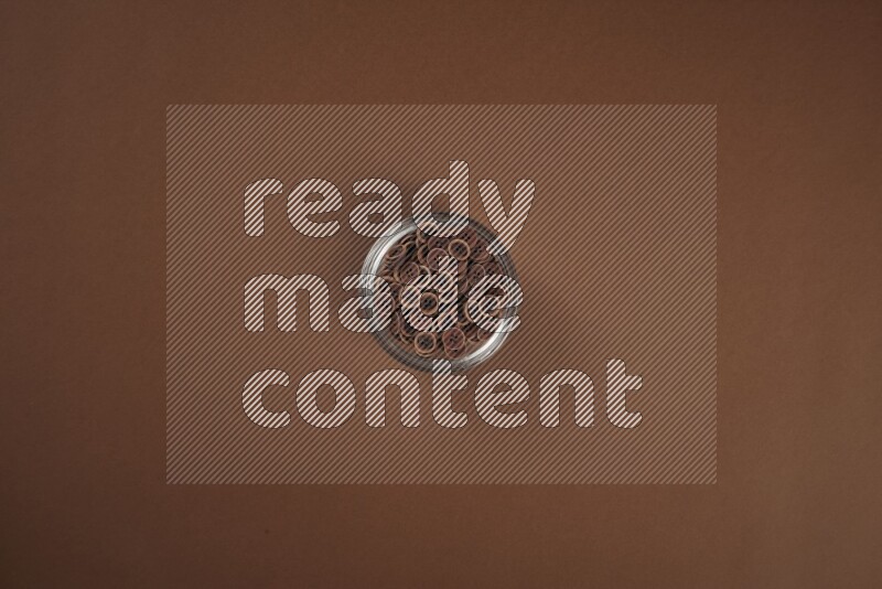 أزرار بنية اللون في وعاء زجاجي على خلفية بنية