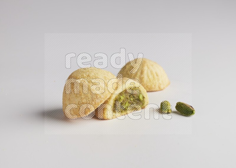 Three Pieces of Maamoul filled with pistachio paste  one of them is cut direct on white background
