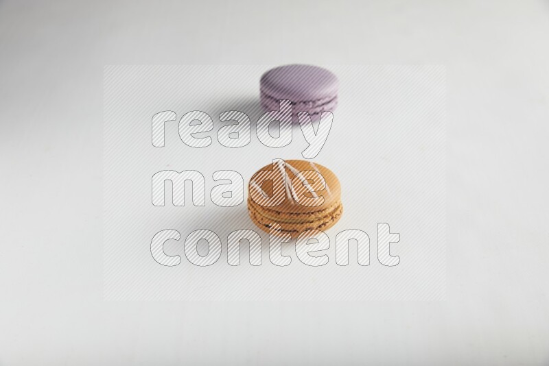 45º Shot of of two assorted Brown Irish Cream, and Purple Blueberry macarons on white background