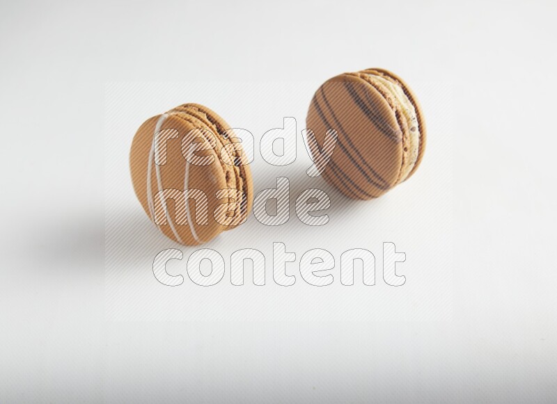 45º Shot of of two assorted Brown Irish Cream, and light brown  Almond Cream macarons on white background