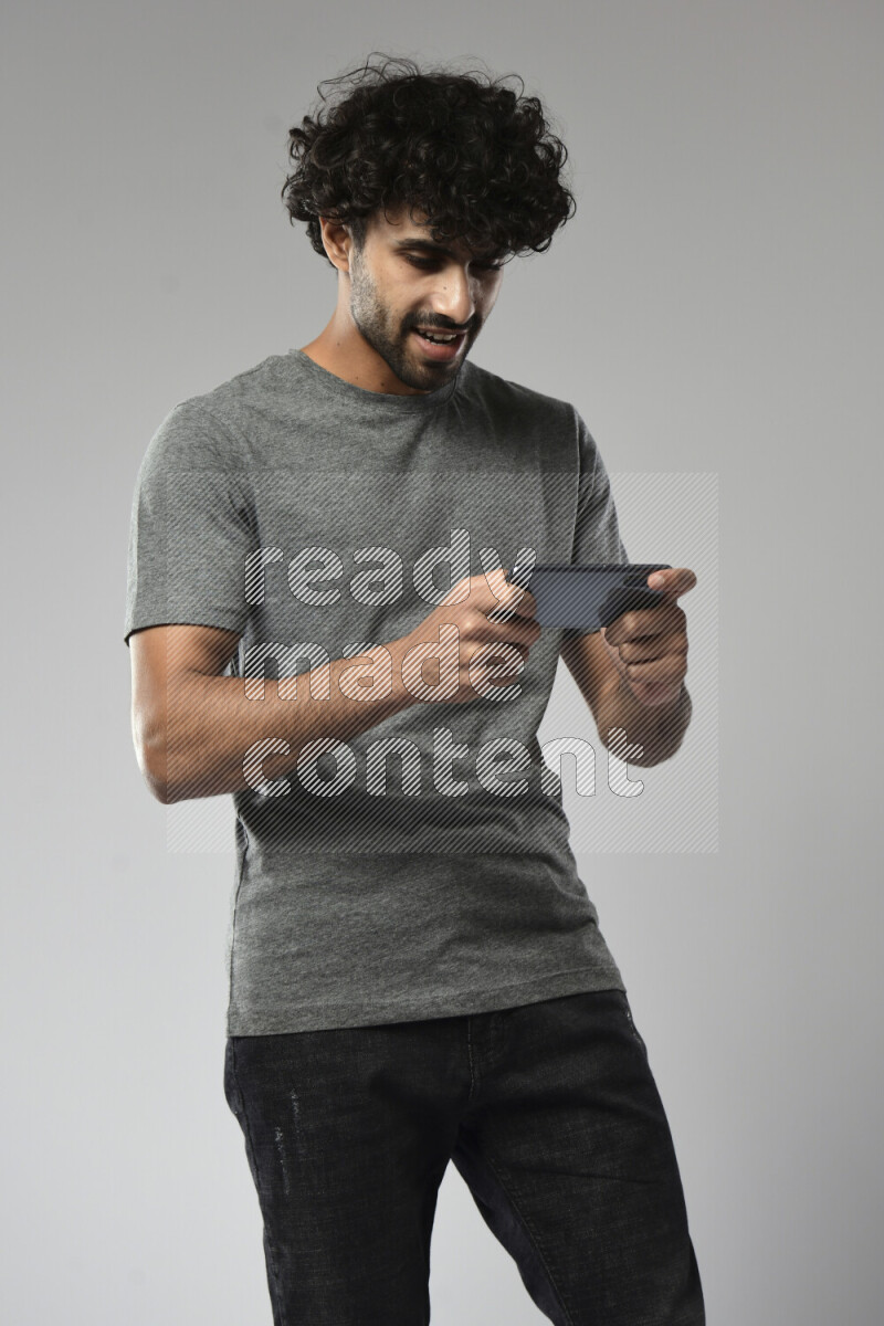 A man wearing casual standing and gaming on the phone on white background