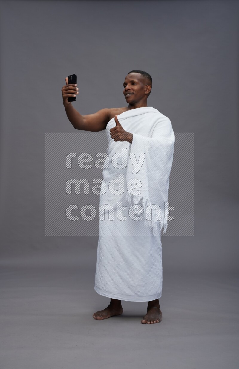 A man wearing Ehram Standing taking selfie on gray background
