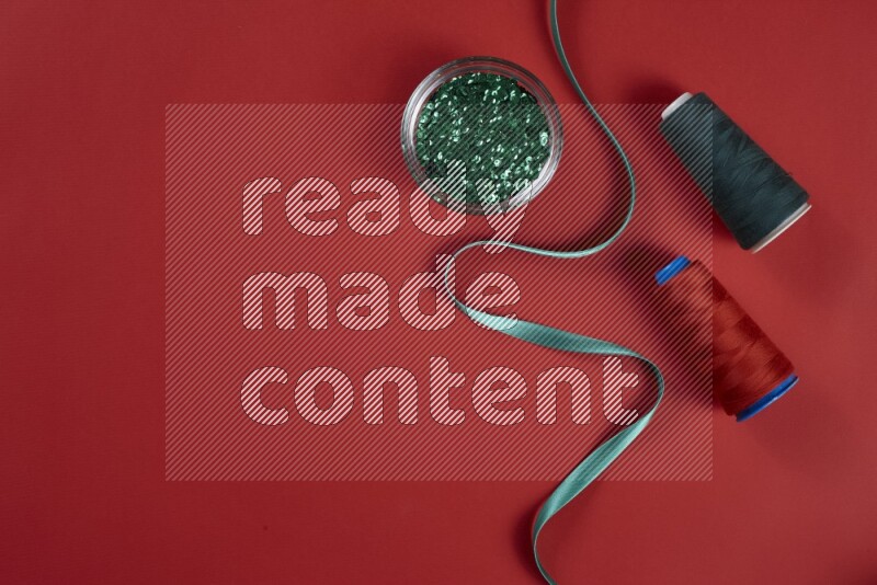 مجموعة من أدوات الخياطة والتفصيل خضراء وحمراء اللون على خلفية حمراء