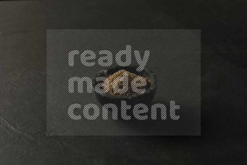 black pottery round sauce bowl filled with herbs on grey textured countertop