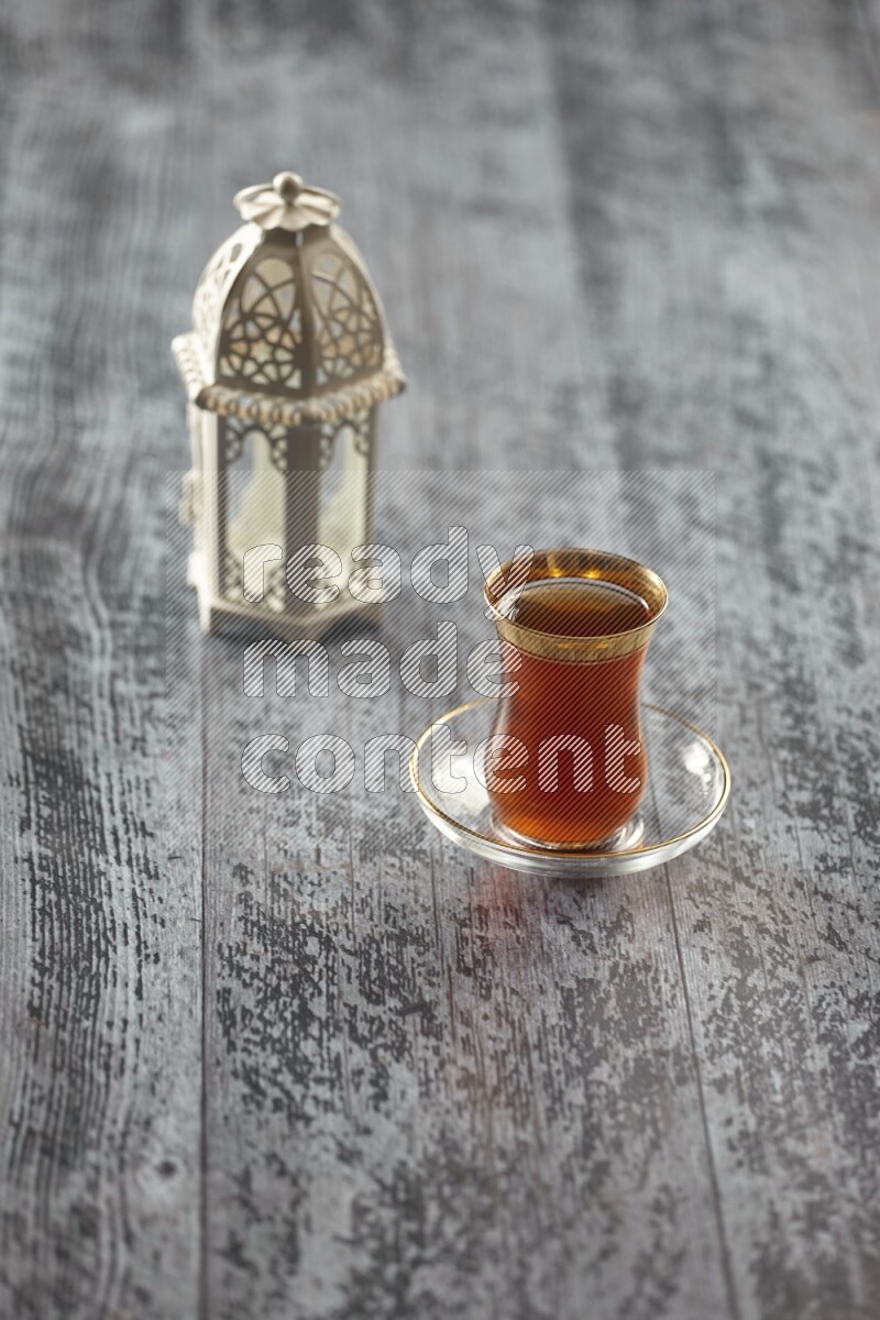 A white lantern with different drinks, dates, nuts, prayer beads and quran on grey wooden background