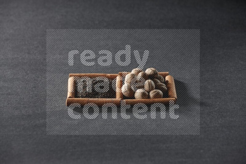 مربعان من أعواد القرفة ممتلئان بالشاي وجوزة الطيب علي خلفية سوداء