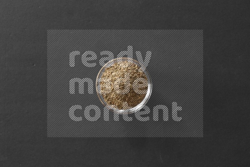 كمون في وعاء زجاجي علي خلفية سوداء